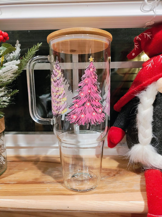 Glass cup with bamboo lid featuring hand-drawn pink Christmas trees, displayed on a windowsill with holiday decor.