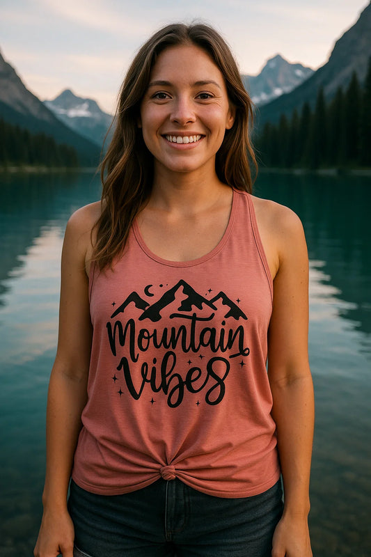 Handmade Mountain Vibes tank top worn by a woman at a lake with mountain scenery, outdoor adventure apparel.