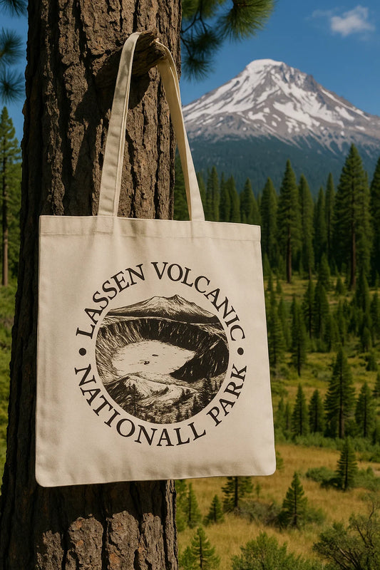 Canvas tote bag printed with Lassen Volcanic National Park crater design, hanging on a tree with Mount Lassen in the background.