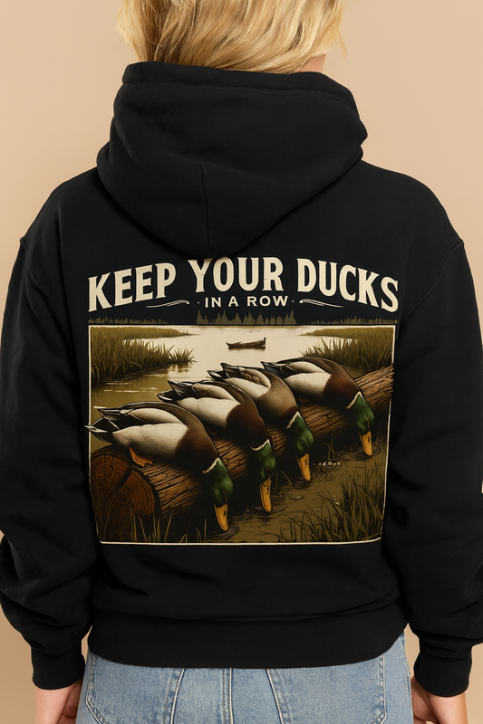 Black Jerzees unisex hoodie with vintage ‘Keep Your Ducks in a Row’ graphic featuring mallard ducks on a log by the water.
