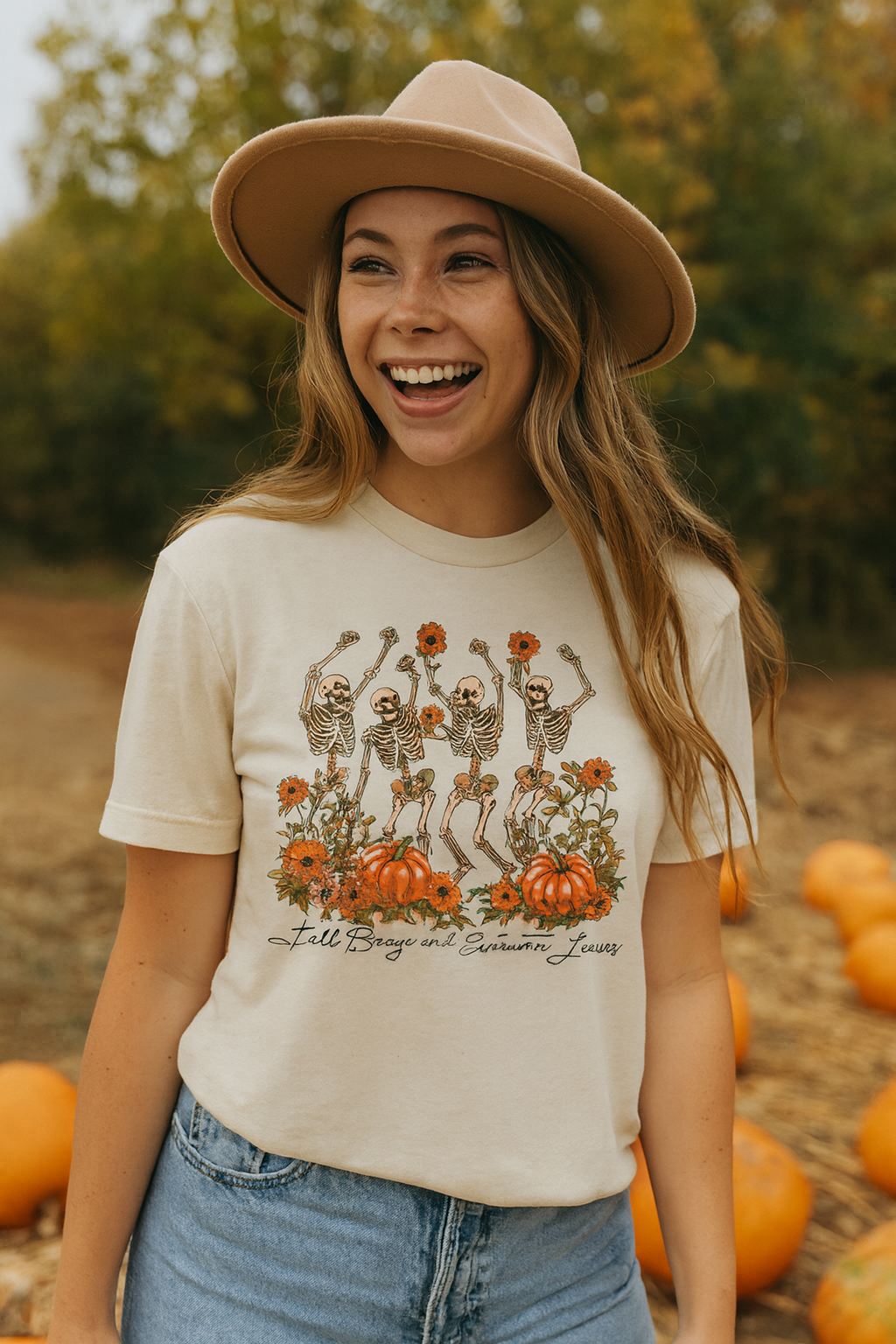 Soft cream Bella+Canvas 3001C t-shirt featuring a vintage-style design of dancing skeletons holding orange flowers, surrounded by pumpkins and autumn blooms, with the words "Fall Breeze and Autumn Leaves" in script.